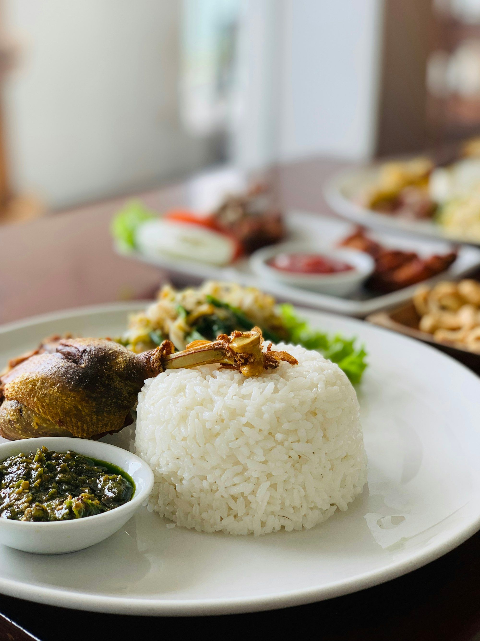 Satu paha bebek goreng utuh dengan nasi putih dan sambal hijau di mangkuk kecil